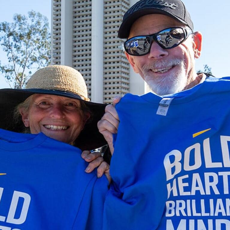 UCR alumnus holding a UCR bold heart. brilliant minds. t-shirt