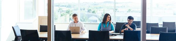 Group of people in a conference room on their computer and talking